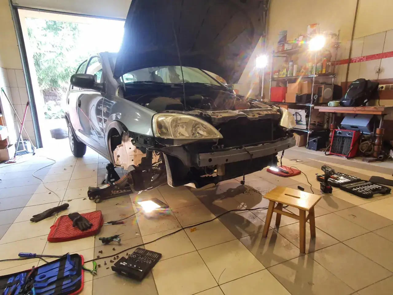 Warsztat samochodowy, auto na podnośniku, w trakcie montażu czujnik&oacute;w parkowania. Narzędzia i sprzęt na podłodze.