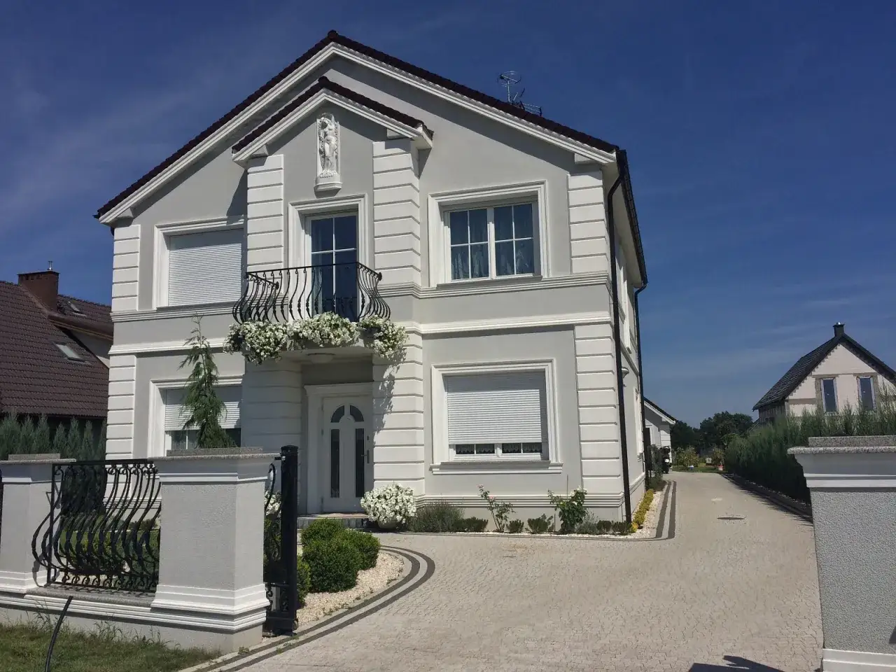 Elegancki dom w stylu angielskim z balkonem ozdobionym kwiatami.