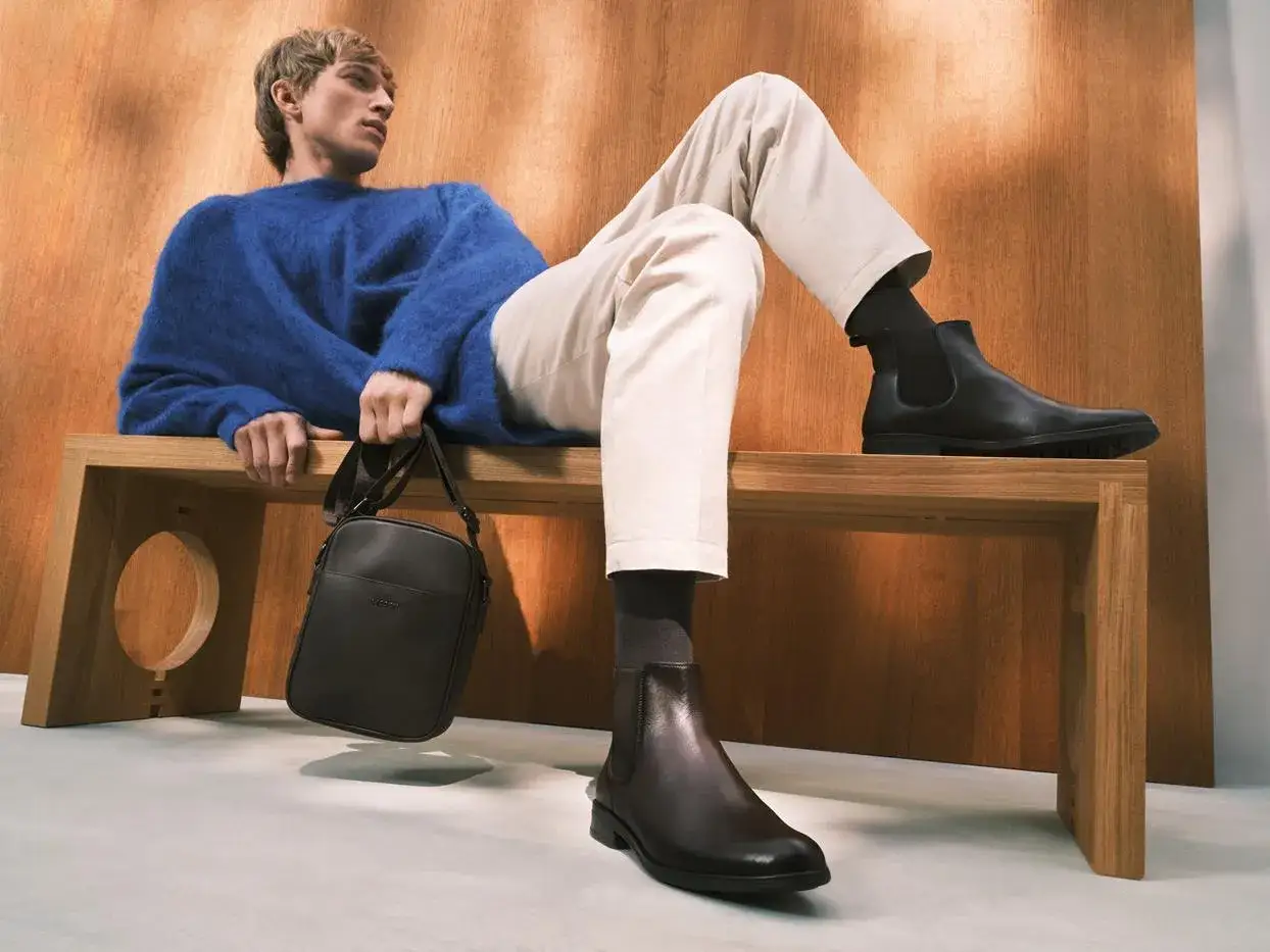 Elegancki mężczyzna w niebieskim swetrze i beżowych spodniach, idealny strój, jak się ubrać do teatru na komedię mężczyzna.