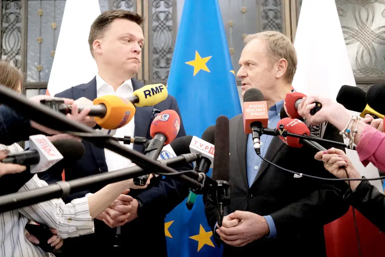 Dwóch liderów partii politycznych otoczonych przez mikrofony mediów.