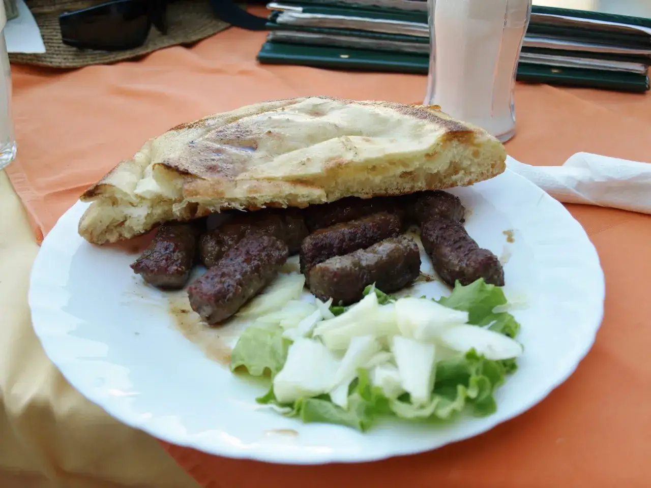 Pyszne ćevapi z chlebem i cebulą, klasyka kuchni bośniackiej, gotowe do zjedzenia.