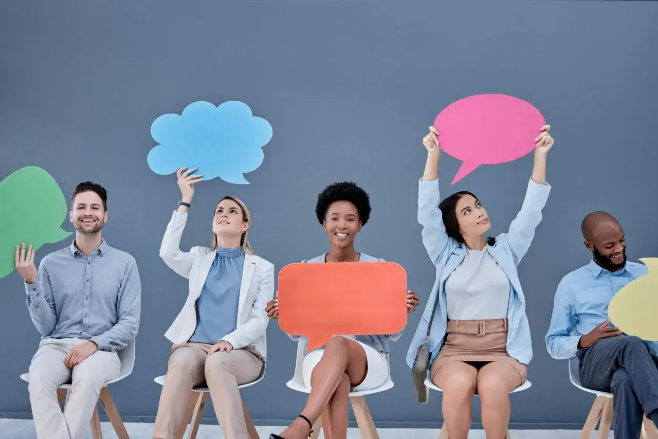 Ludzie siedzą w rzędzie, trzymając kolorowe dymki. Może to być symbol przeprosiny prosto z serca, wyrażone słowami.