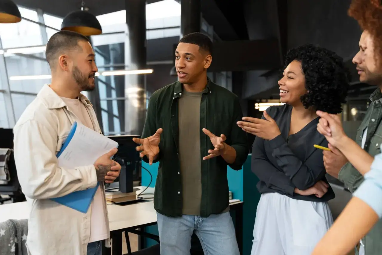 Ludzie w biurze dyskutują, pokazując cechy dobrego słuchacza: zaangażowanie, kontakt wzrokowy i aktywne słuchanie.