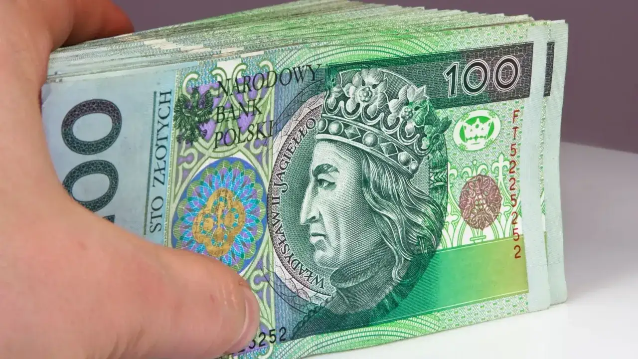 Stos banknotów 100 zł, trzymany w dłoni. Tyle pieniędzy, a i tak nigdy nie wygrasz w lotto.
