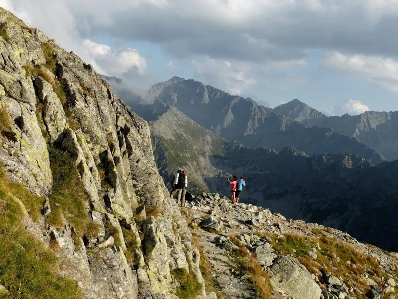 Trzej turyści na skalistym szlaku na Zawrat, podziwiający majestatyczne Tatry.