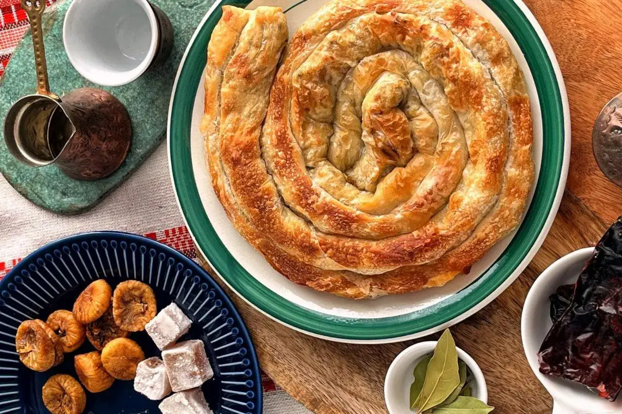 Złocisty, zwinięty w spiralę placek, symbol kuchni bałkańskiej, podany z suszonymi figami i lokum.