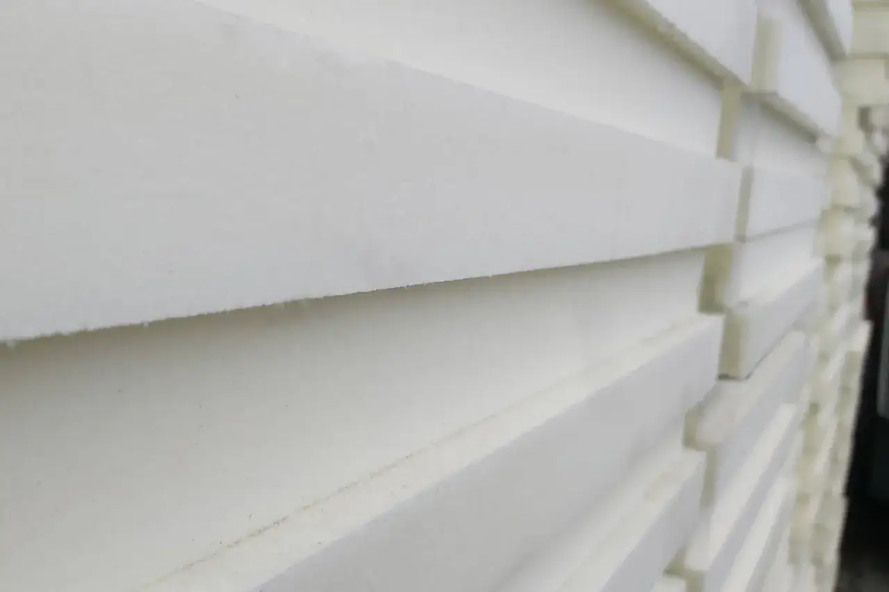 Stos białych płyt styroduru, idealnych do izolacji. Zastanawiasz się, czym malować styrodur? Wybierz farby akrylowe lub lateksowe.