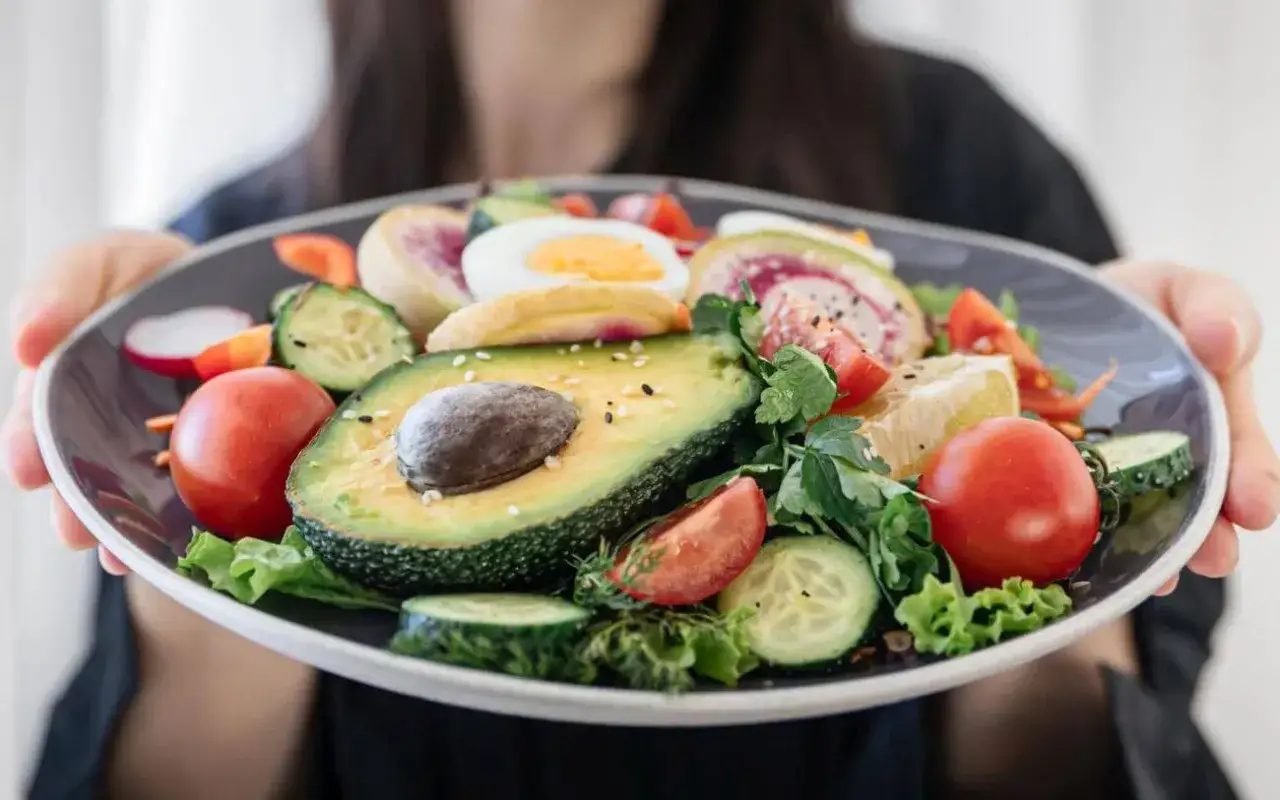 Talerz pełen świeżych warzyw i jajka, idealny na dietę 1100 kcal. Awokado, pomidory, ogórek i rzodkiewka tworzą kolorową kompozycję.