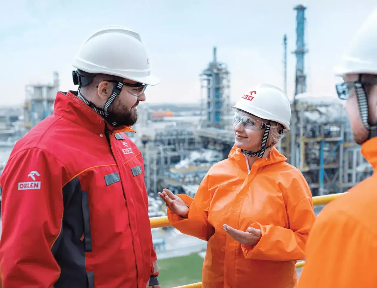 Pracownicy Orlenu w kombinezonach omawiają pracę. Ciekawe, ile zarabia pracownik Orlenu?