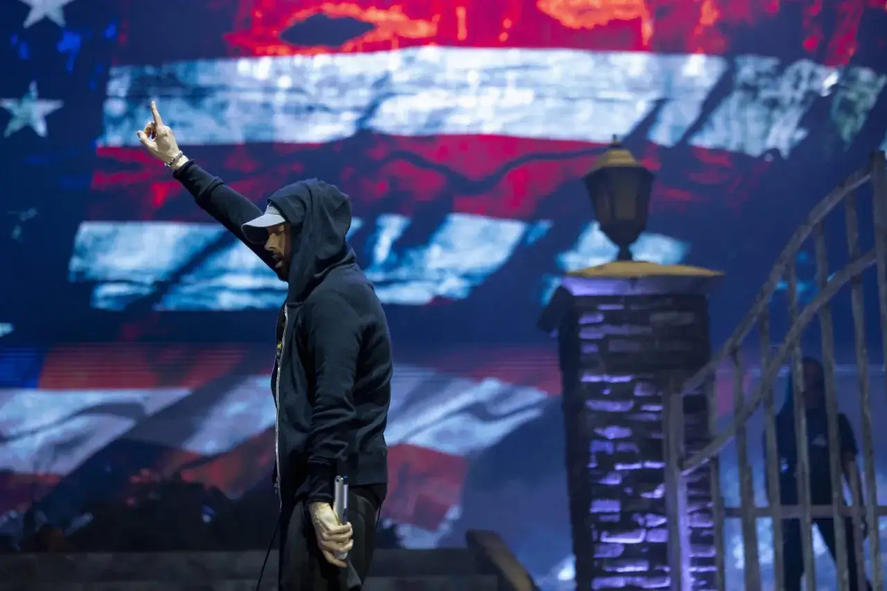 Eminem na scenie z amerykańską flagą w tle. Wskazuje palcem w górę, jakby chciał powiedzieć, że jeszcze nie zmarł.