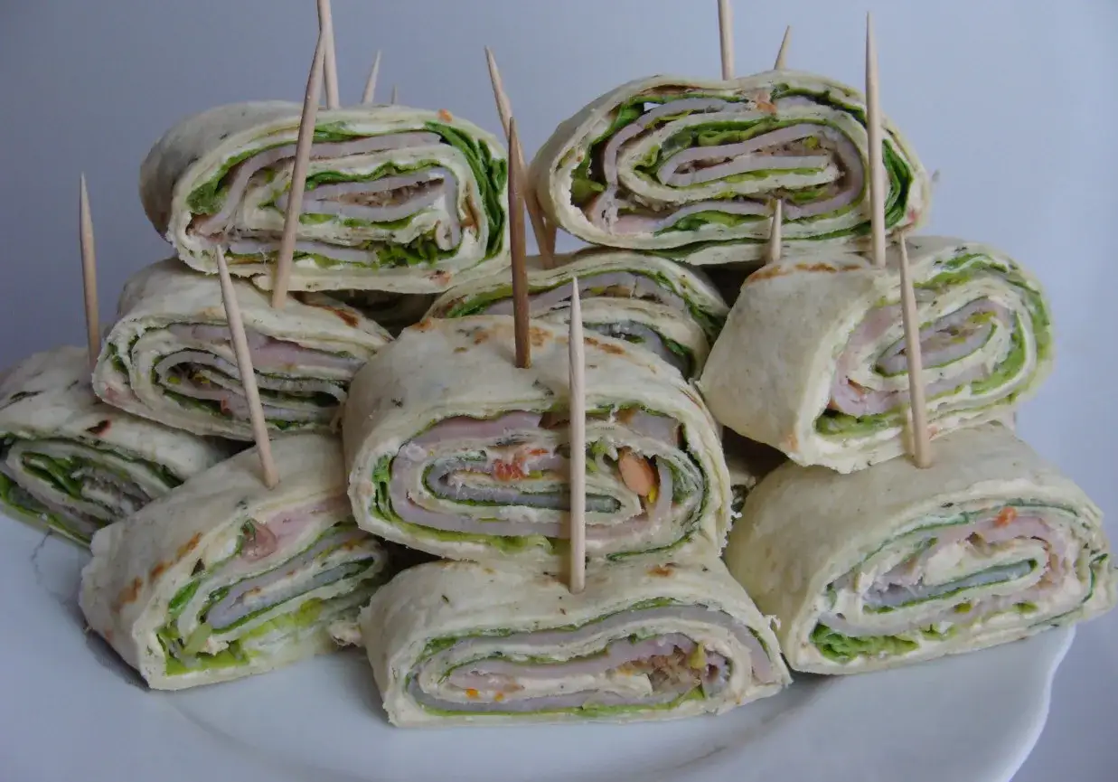 Roladki z tortilli z szynką i serem, świeżą sałatą i kremowym sosem, zabezpieczone wykałaczkami. Idealne na ciepło.