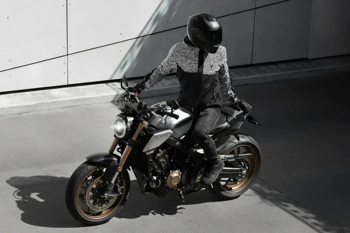 Motocykl sportowy w nowoczesnym wydaniu, gotowy na miejską dżunglę. Kierowca w kasku i stylowej kurtce.