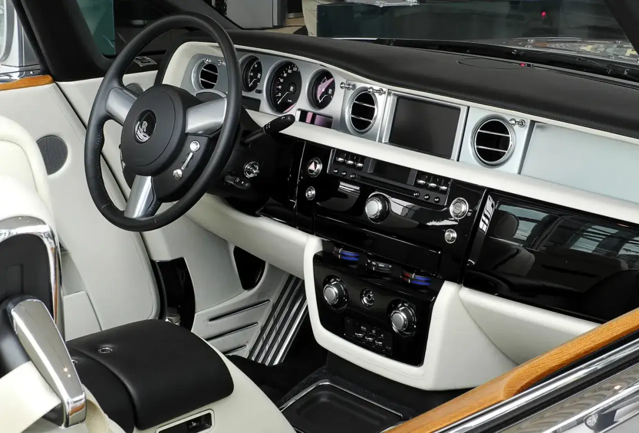Wnętrze Rolls-Royce Phantom Drophead Coupe: biała skóra, czarny lakier, drewniane akcenty i elegancka kierownica.