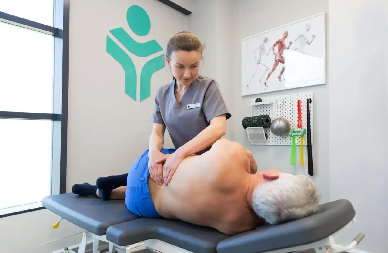 Fizjoterapeuta pomaga pacjentowi z bólem kręgosłupa