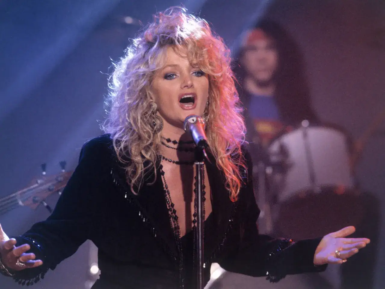 Bonnie Tyler na scenie, śpiewająca z pasją. W tle zesp&oacute;ł. Ile lat ma Bonnie Tyler?