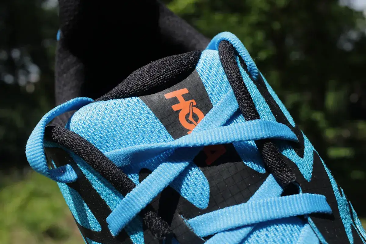 Niebieskie buty Hoka Challenger 8 z czarnymi akcentami i pomarańczowym logo. Gotowe na przygodę!