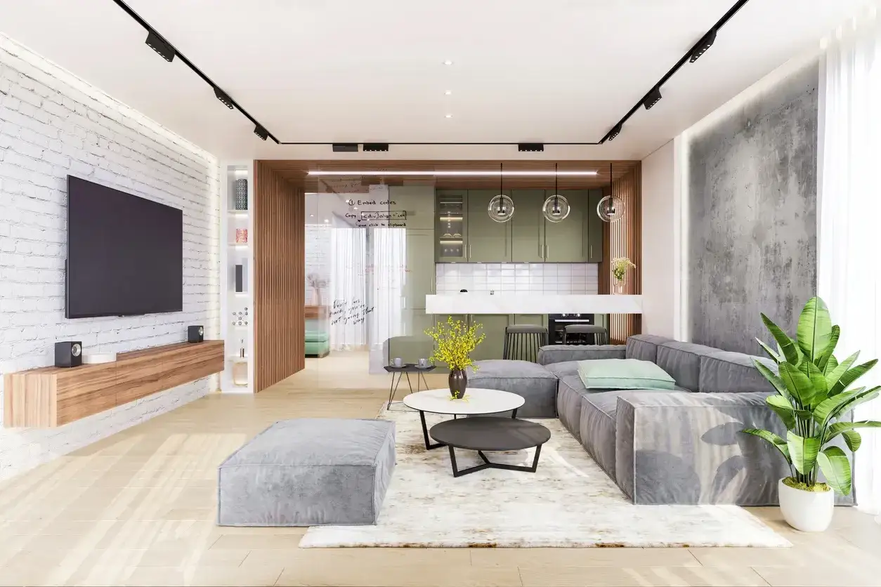 Nowoczesne wnętrze z szarą sofą, stolikami kawowymi i kuchnią w tle. Ciepłe światło w salonie tworzy przytulną atmosferę.