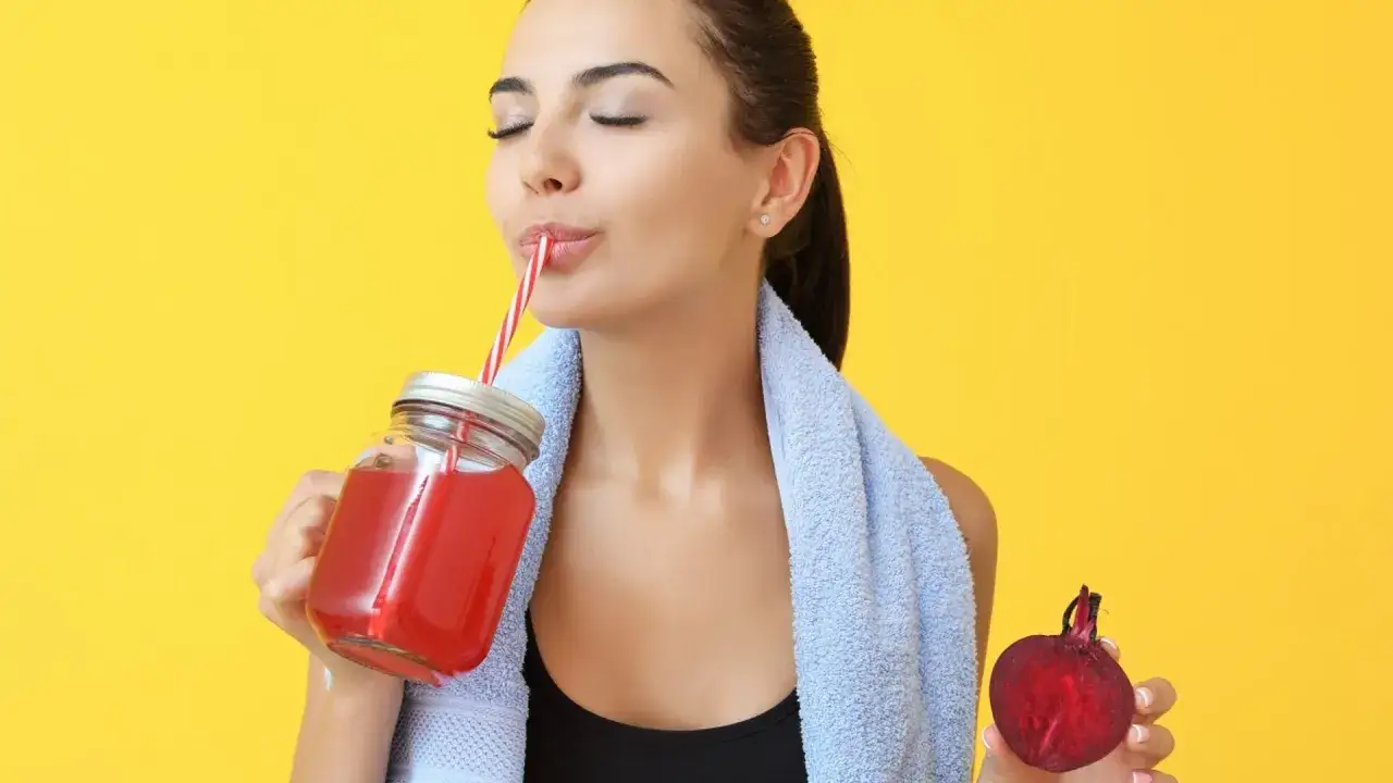 Kobieta pije sok z buraka, kt&oacute;ry jest świetny na odporność i energię. Obok trzyma świeżego buraka.