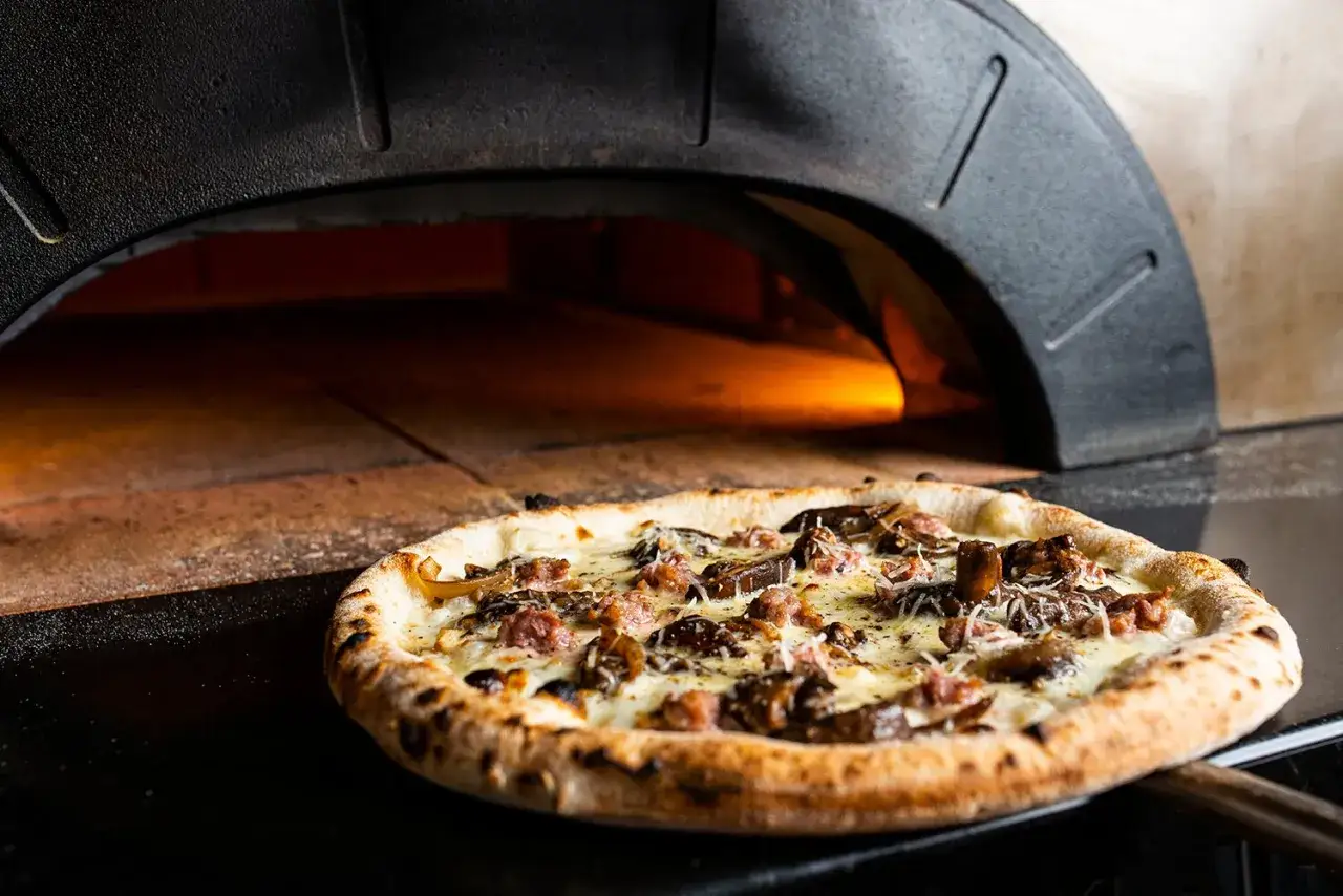 Pyszna pizza z pieca opalanego drewnem w pizzeria stare miasto. Gorąca, z ciągnącym się serem i chrupiącymi dodatkami.