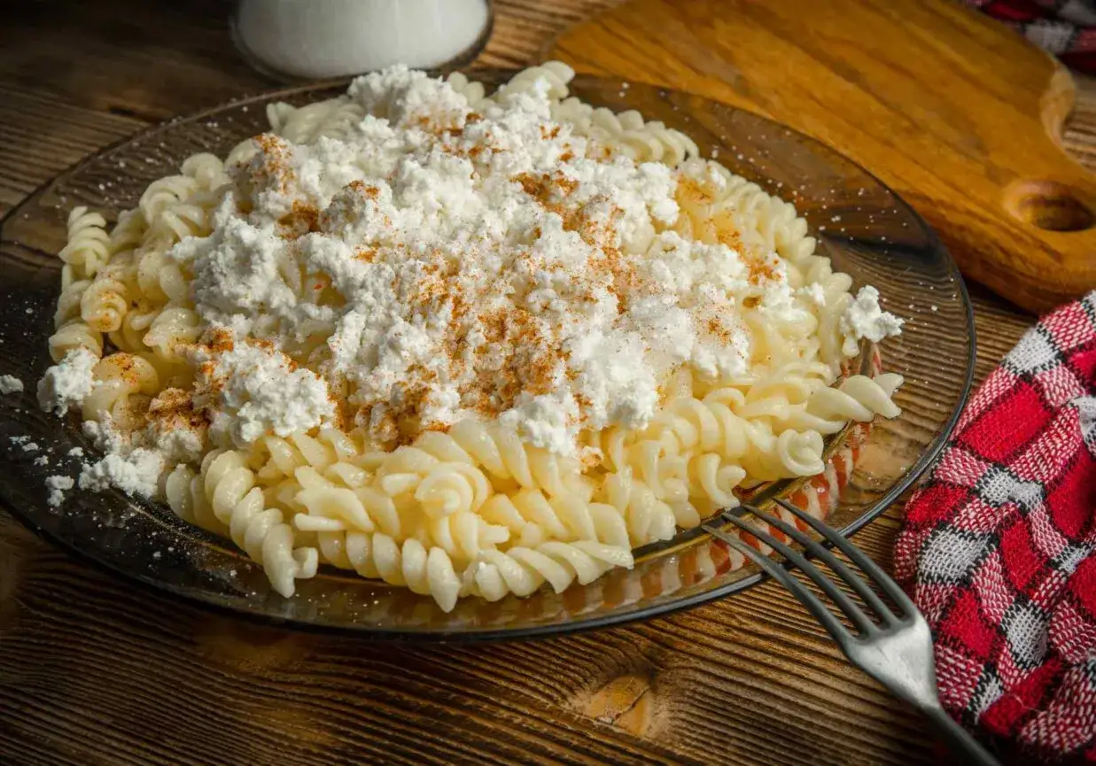 Pyszny makaron z twarogiem i posypką z papryki na talerzu.