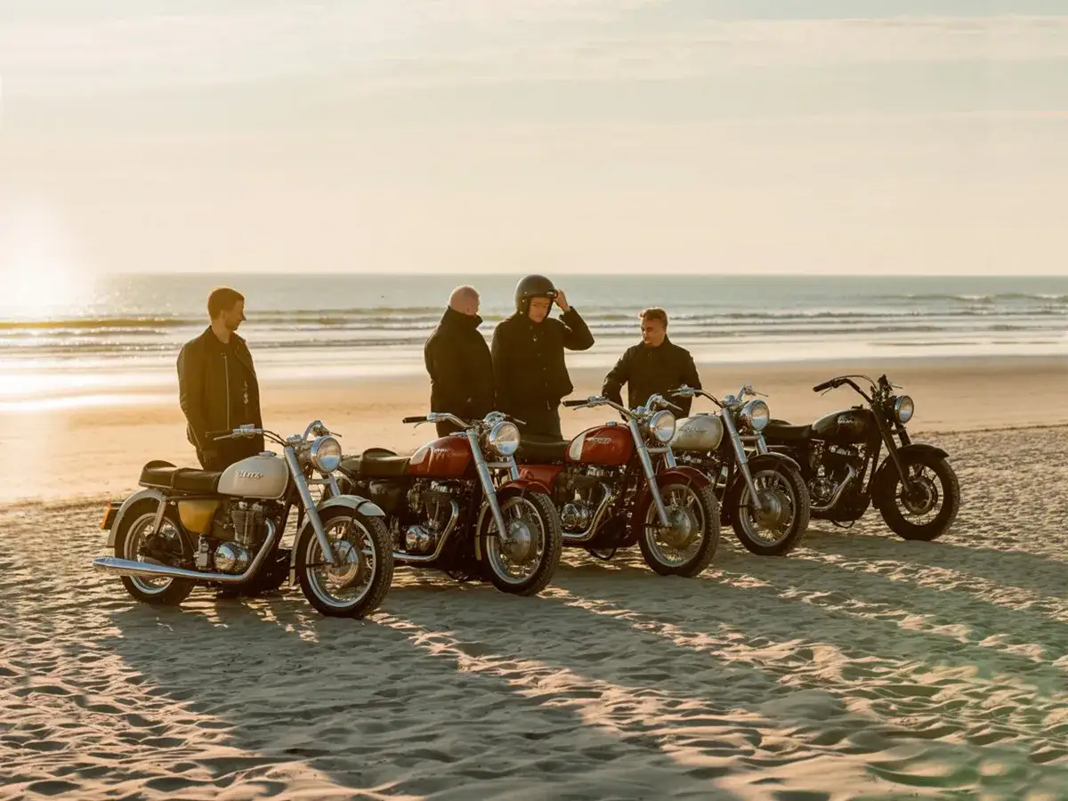 Czterech mężczyzn i ich motocykle na plaży, gotowi na przejażdżkę nad morze.