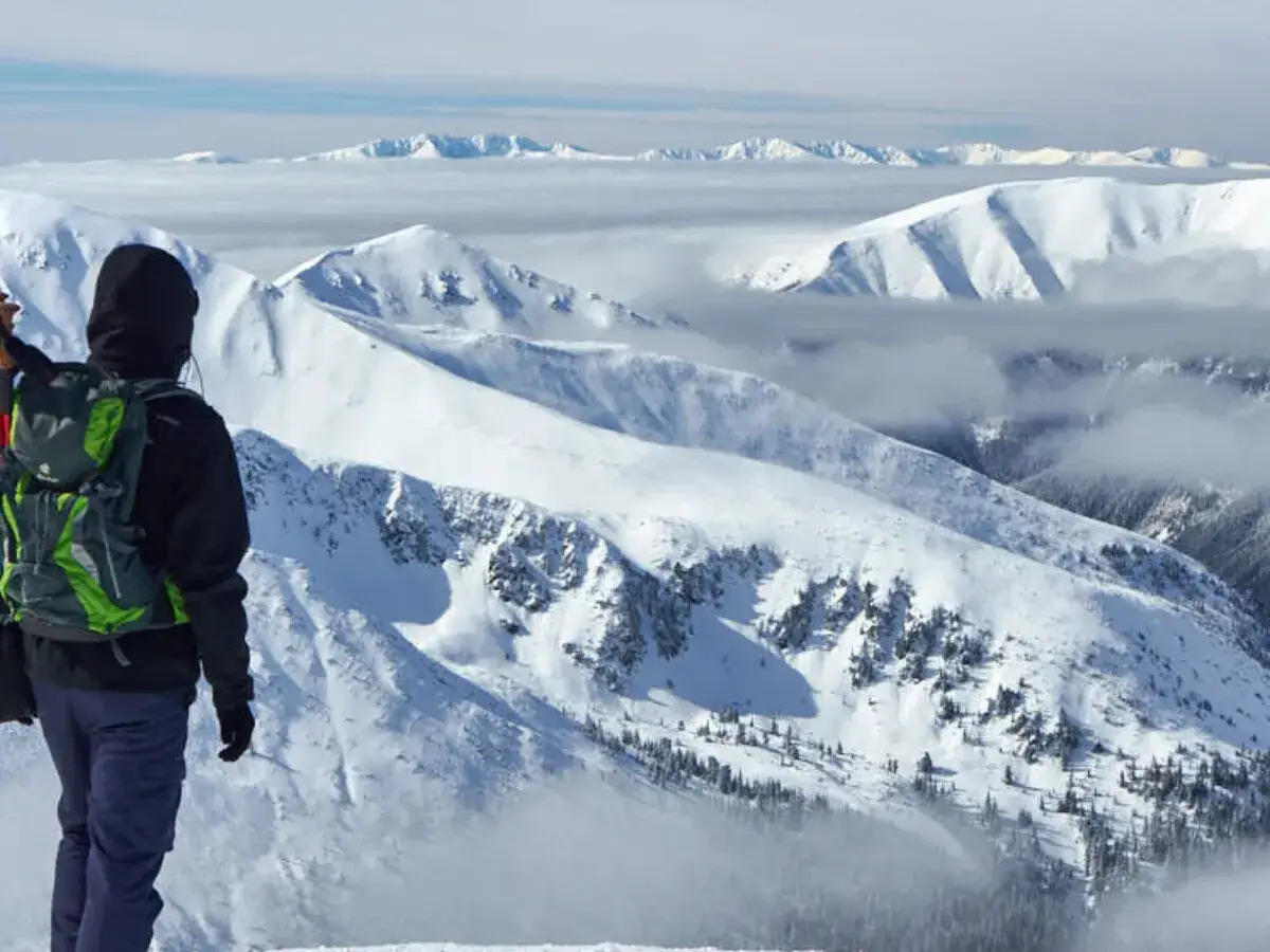 Widok na ośnieżone szczyty Tatr z perspektywy turysty, kt&oacute;ry właśnie dotarł na wejście na Kasprowy Wierch.