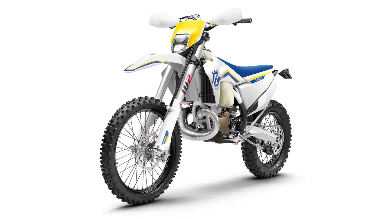 Biały motocykl Husqvarna TE 250 z niebieskim siedzeniem i ż&oacute;łtymi akcentami, gotowy na terenowe wyzwania.