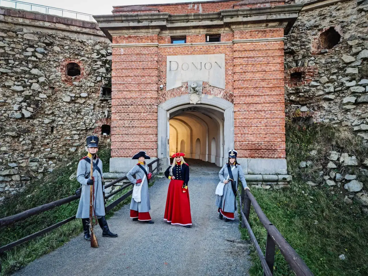 Cztery osoby w strojach historycznych przed bramą twierdzy. Srebrna G&oacute;ra atrakcje historyczne.