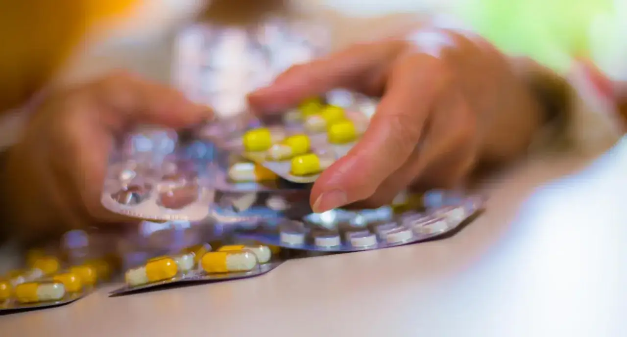 Dłonie trzymają opakowania z lekami. Zastanawiam się, jaki odstęp między antybiotykiem a ibuprofenem jest bezpieczny.