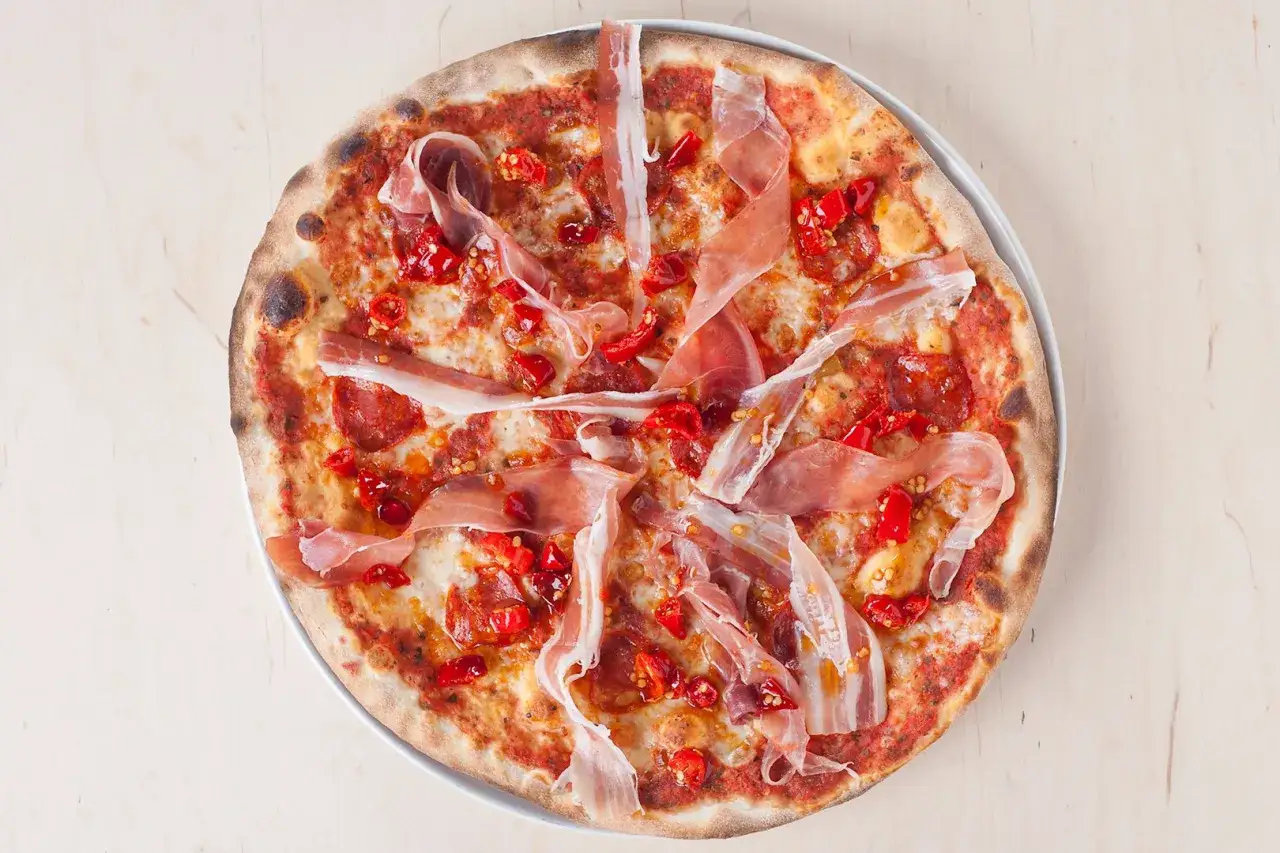 Pikantna pizza z prosciutto i papryczkami, idealna odpowiedź na pytanie, gdzie zjeść w Tomaszowie Mazowieckim.