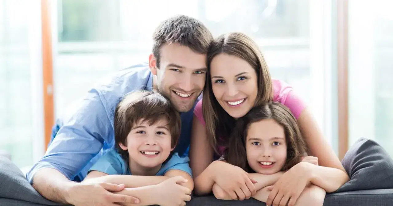 Szczęśliwa rodzina, która właśnie dowiedziała się, jak adoptować dziecko. Uśmiechnięci rodzice i dwójka dzieci.