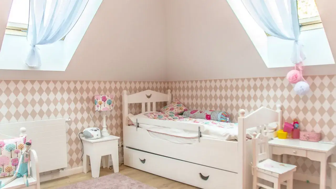 Uroczy pokój dla chłopca 4 lata. Białe łóżko z szufladami, kolorowe poduszki, lampka z motywem drzewek i dywanik.