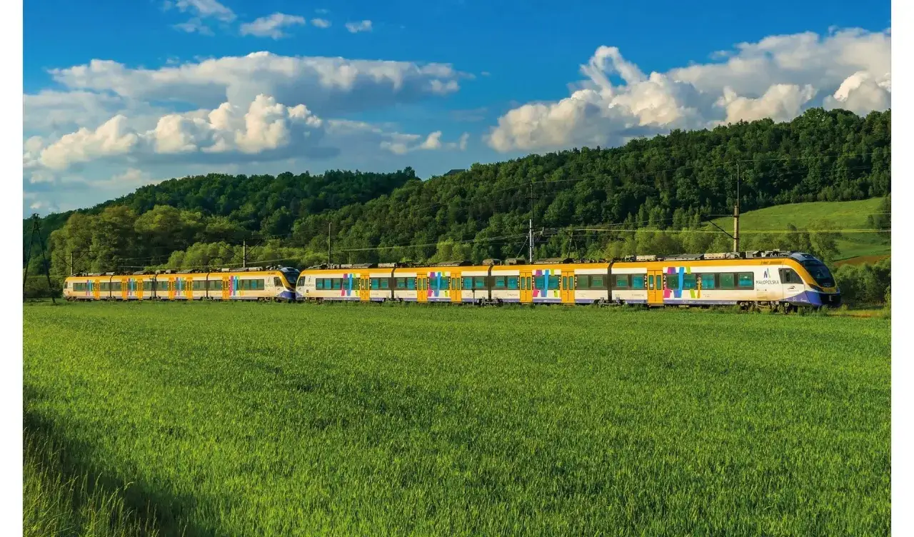 Pociągi Kolei Małopolskich na tle zielonych pól i lasów. Sprawdź nowy rozkład jazdy i podróżuj po Małopolsce!