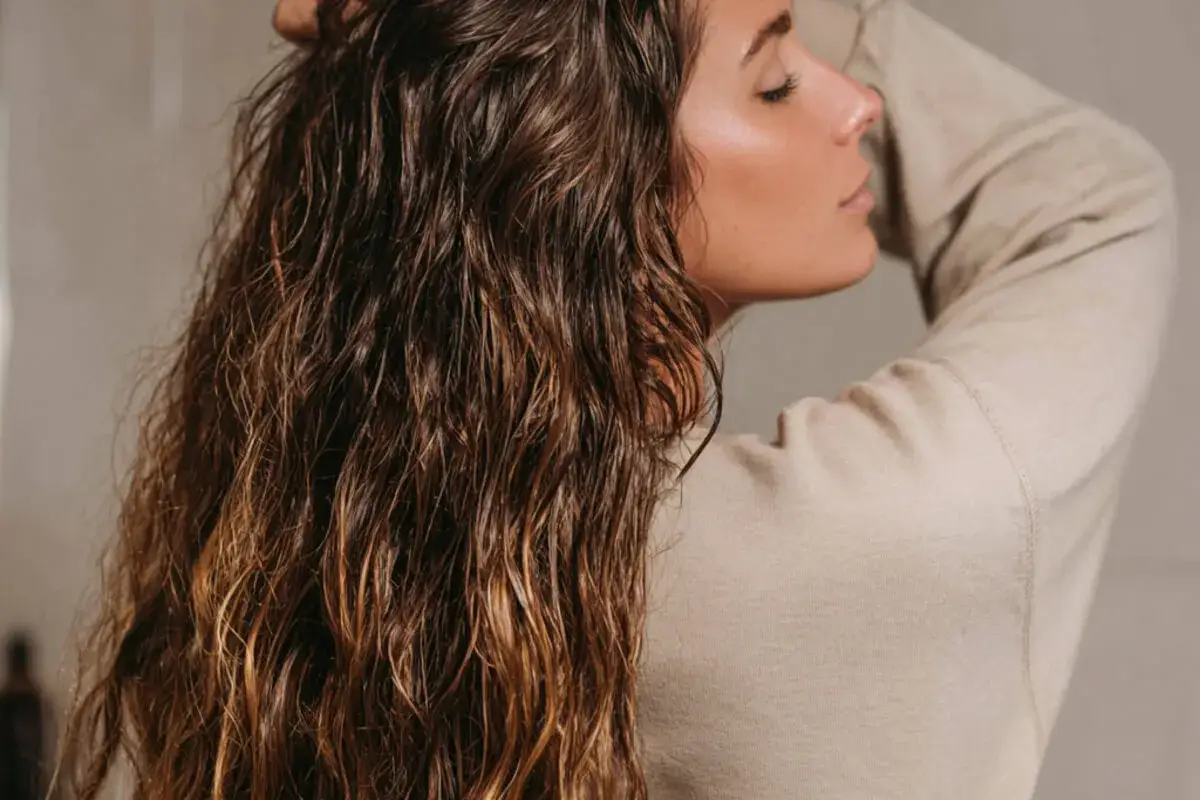 Naturalne fryzury dla włosów falowanych puszących się. Delikatne fale podkreślają piękno długich, brązowych włosów.