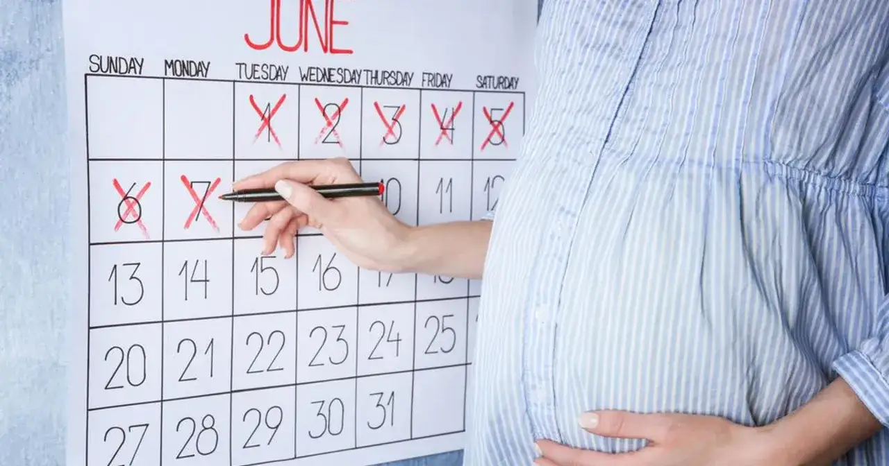 Ciężarna kobieta zaznacza na kalendarzu datę wizyty, kiedy badania prenatalne.