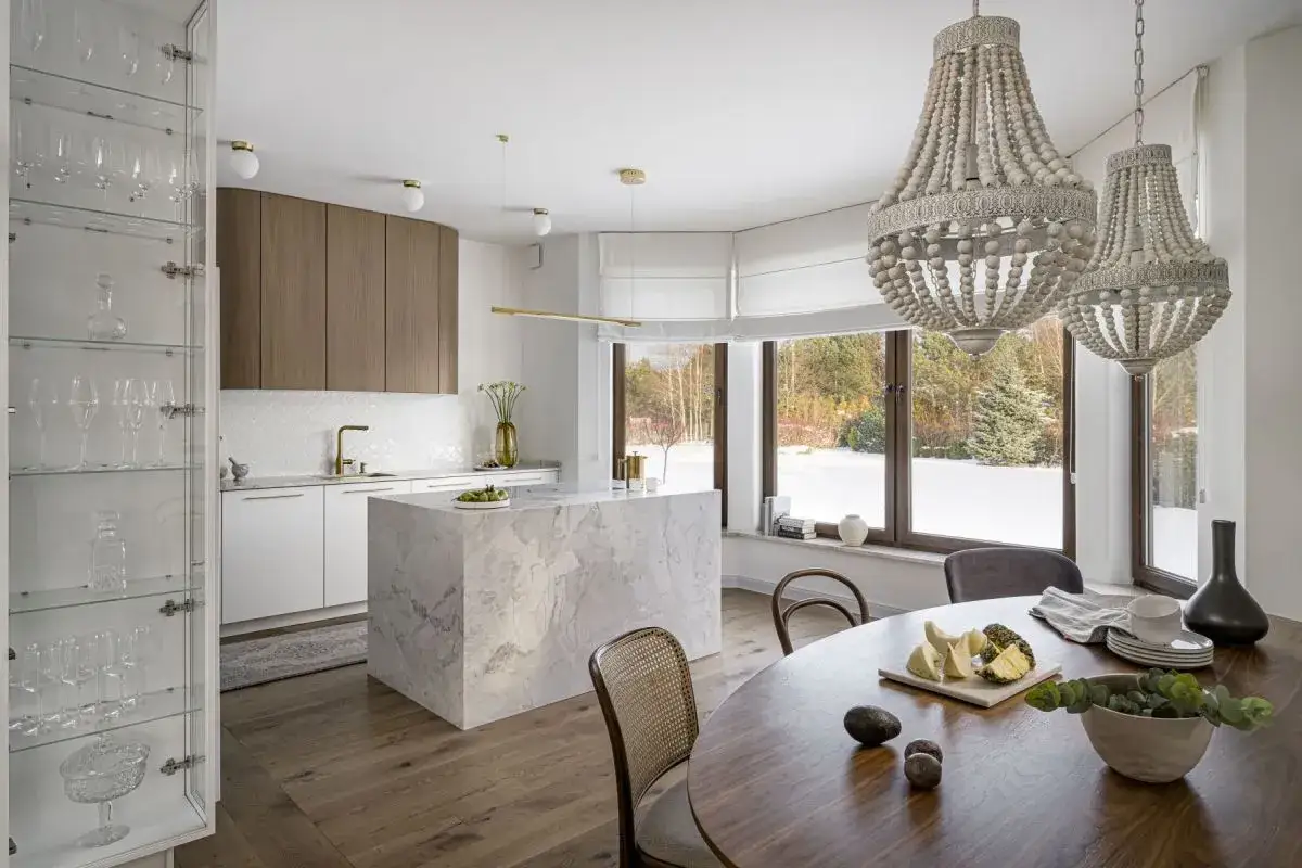Elegancka kuchnia modern classic z marmurową wyspą, drewnianymi frontami i kryształową witryną.