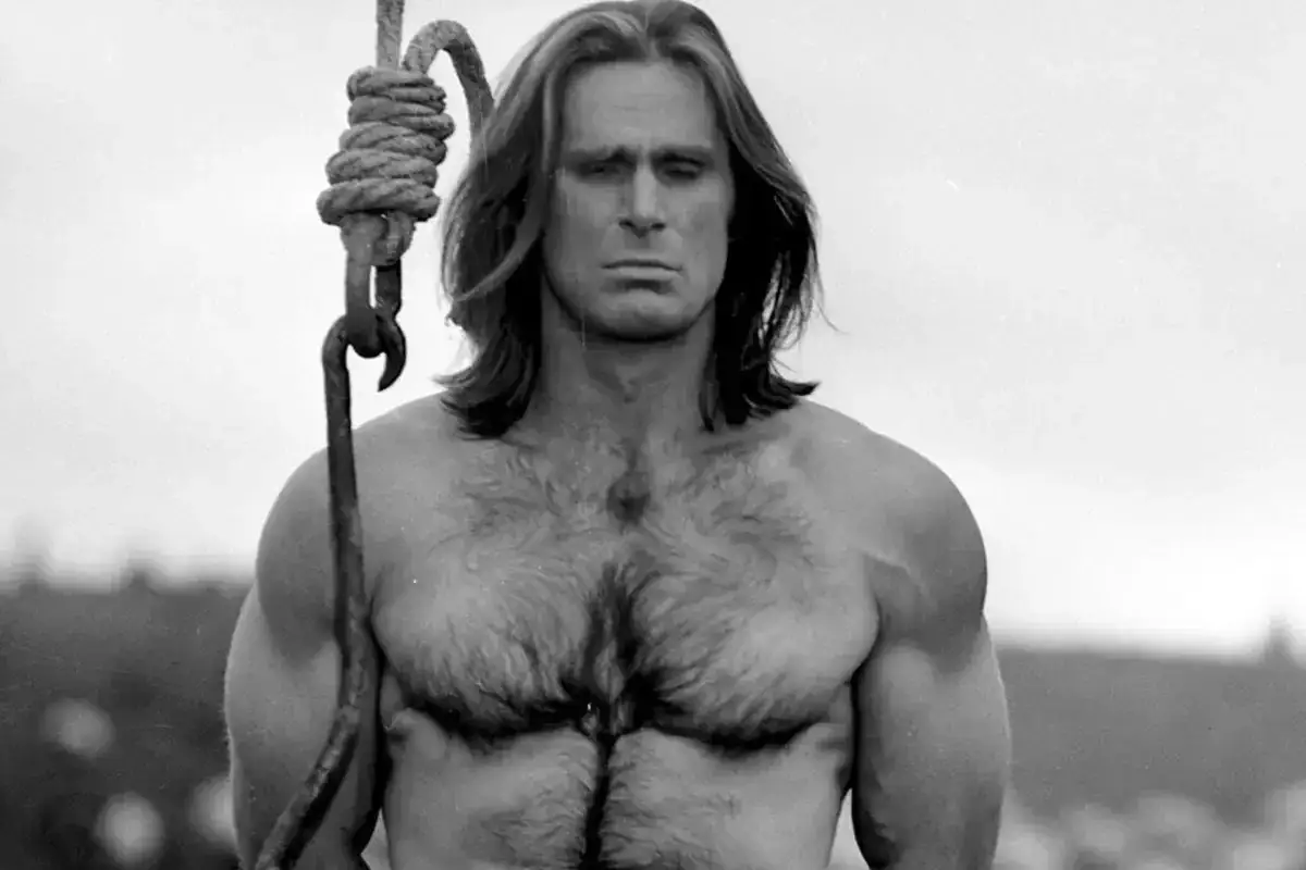 Mocny mężczyzna z długimi włosami, w kadrze z filmu Jerzego Passendorfera.