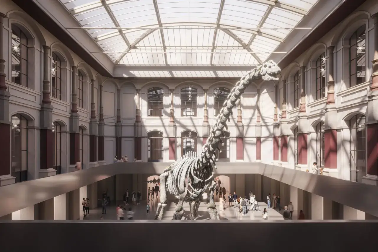 Imponujący szkielet dinozaura w przestronnej sali muzeum w Berlinie. Zwiedzający podziwiają gigantyczne kości pod szklanym dachem.
