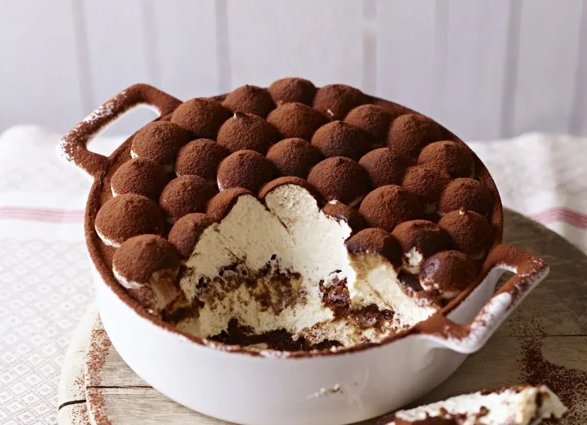 Puszyste tiramisu bez jajek, udekorowane kakao, w białej misie z uchwytami. Idealne na deser.