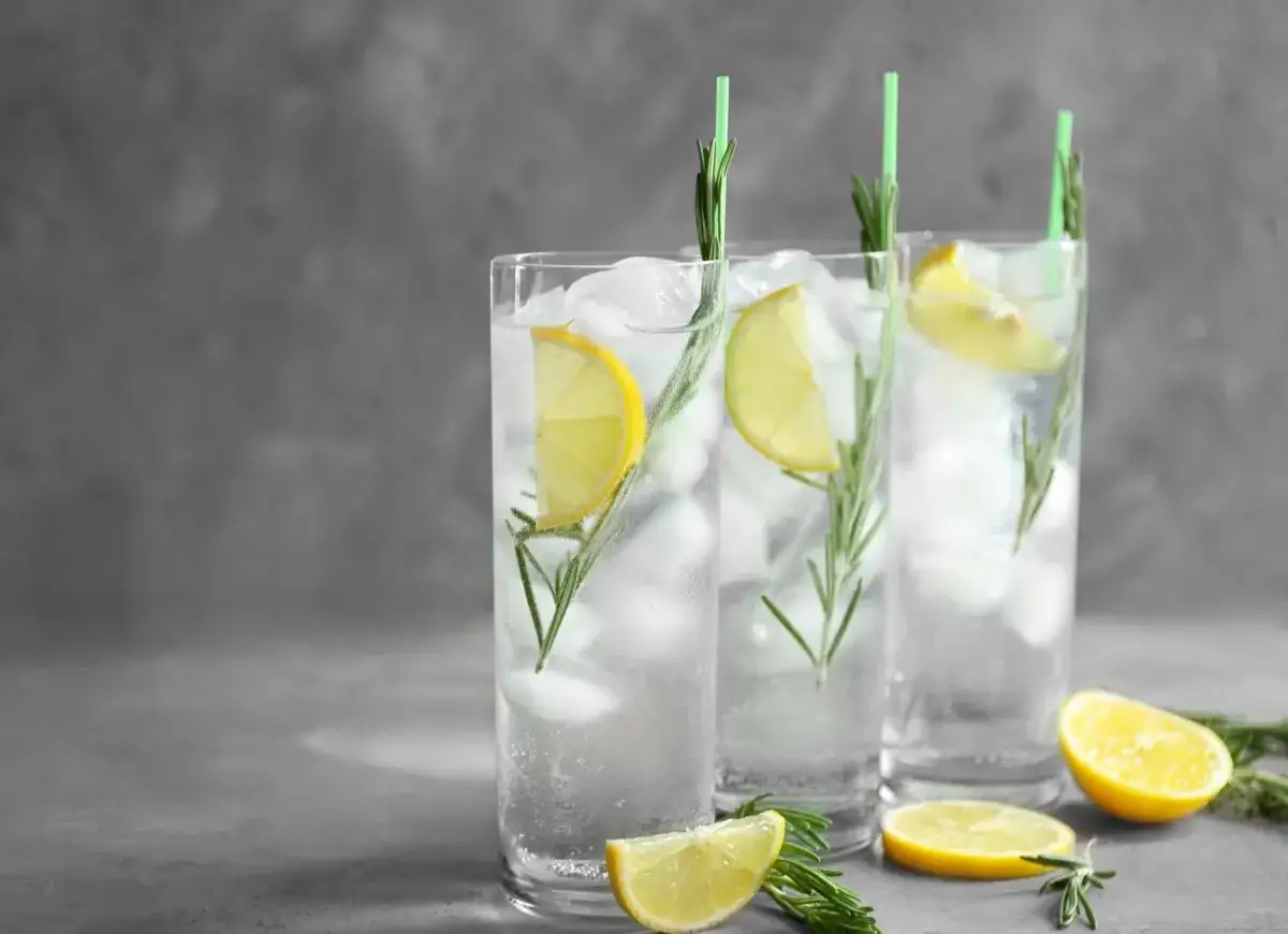 Trzy orzeźwiające gin fizz drinki z lodem, plasterkami cytryny i gałązkami rozmarynu.