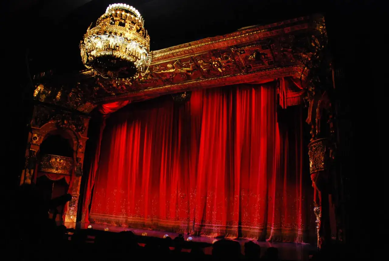 Złoty żyrandol i czerwone zasłony sceny Teatru Wielkiego w Warszawie, jakby z 