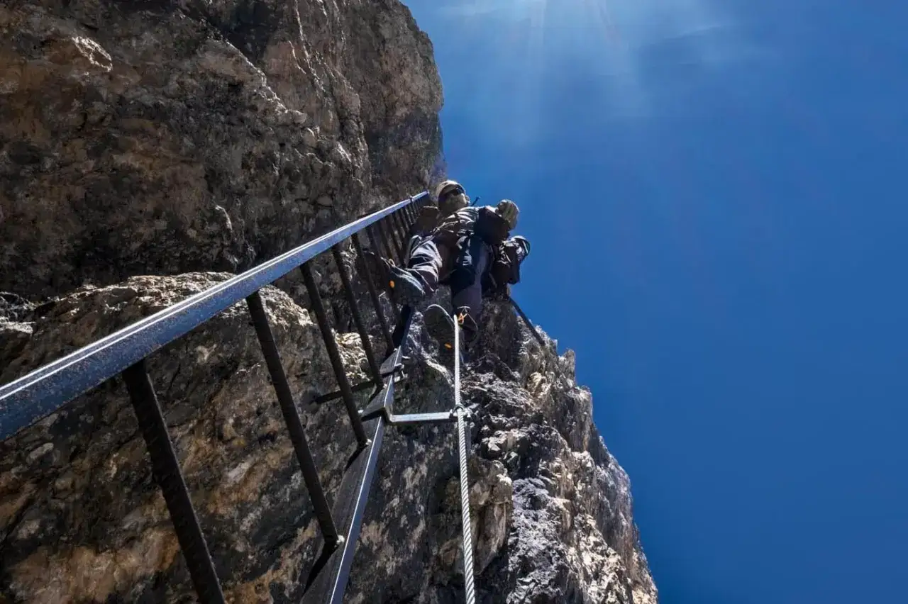 Wspinaczka po drabinie na skalnej ścianie w Dolomitach. Ekscytująca przygoda na ferratach.