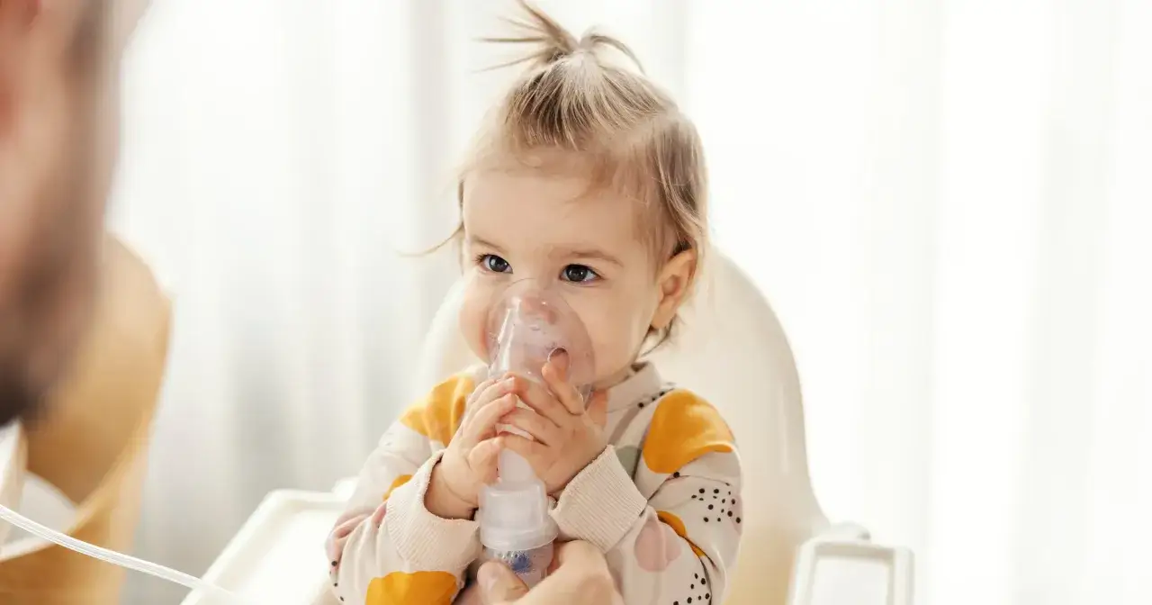Małe dziecko z maską inhalatora na twarzy. Dobre inhalacje dla niemowlaka to klucz do zdrowia.