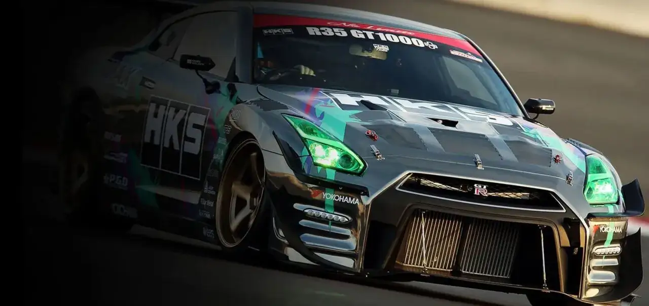 Wyścigowy Nissan GT-R R35 z zielonymi światłami i grafiką HKS.