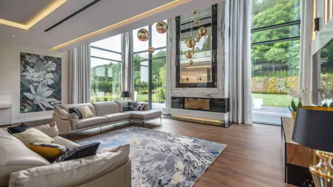 Nowoczesny salon z panoramicznym oknem tarasowym, wygodną sofą i designerskim kominkiem.