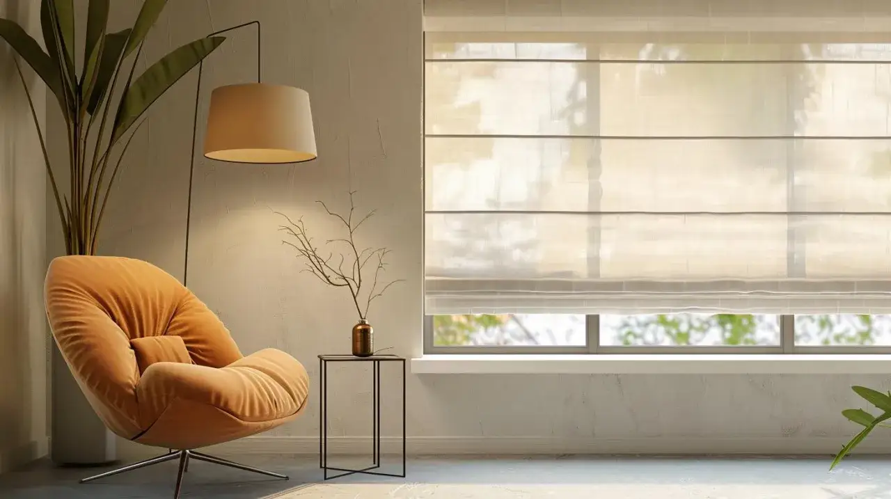 Miękka, pomarańczowa sofa obok okna z zasłoniętą roletą rzymską białą, przez którą przebija światło.