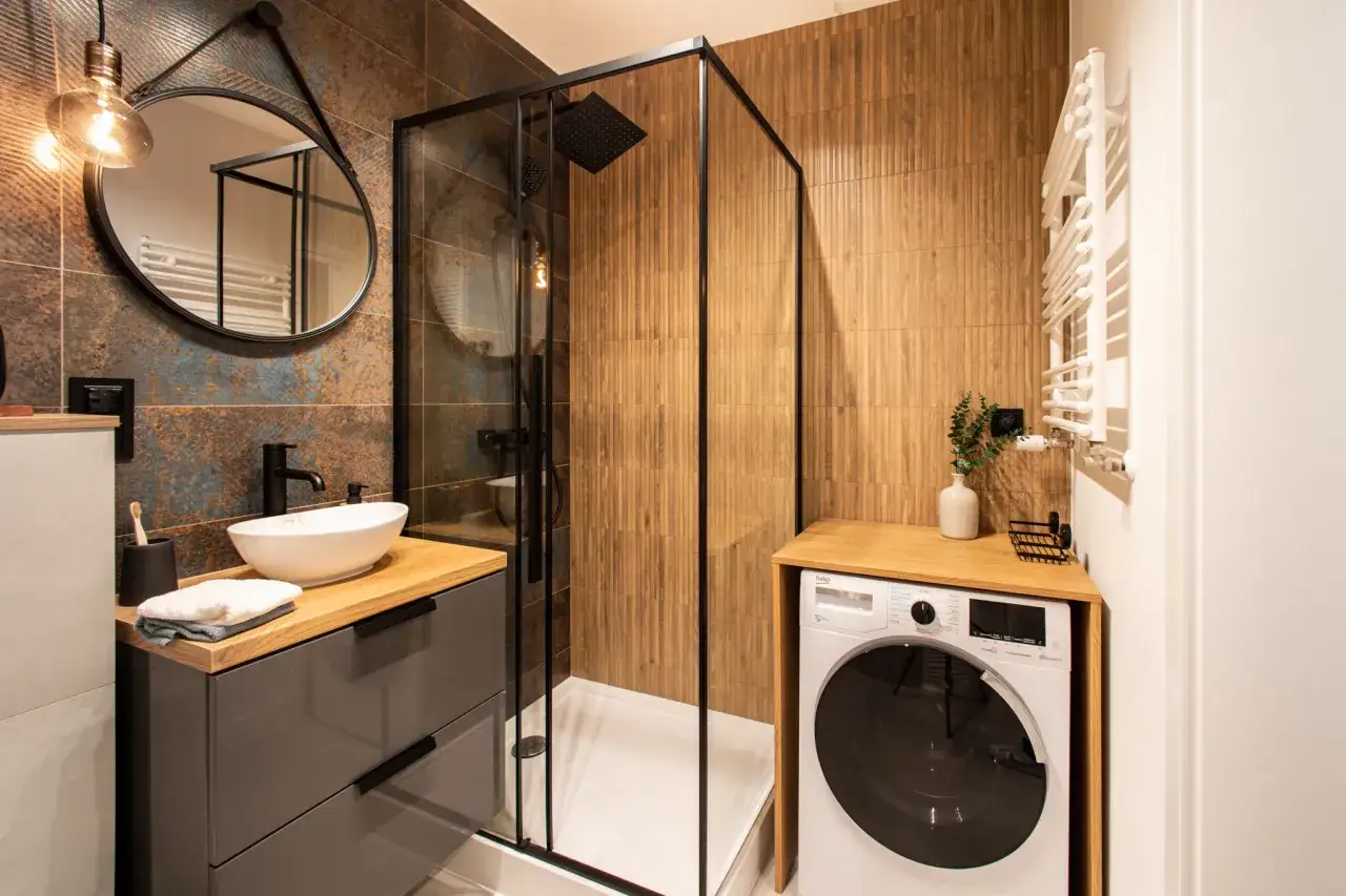 Nowoczesna łazienka 2m2 z pralką, prysznicem walk-in, umywalką nablatową i stylowymi, drewnopodobnymi płytkami.