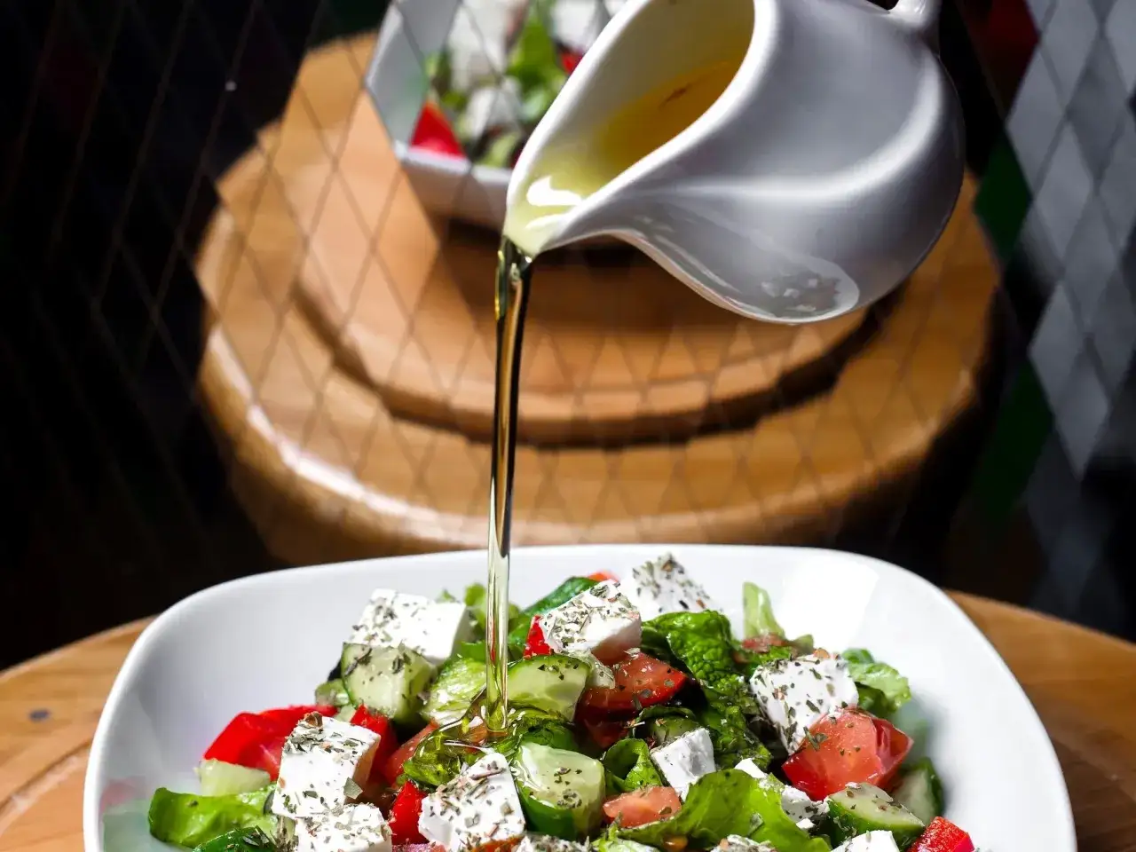 Oliwa z oliwek spływa na świeżą sałatkę z fetą, pomidorami i og&oacute;rkiem. Idealny przepis na zdrową sałatkę.