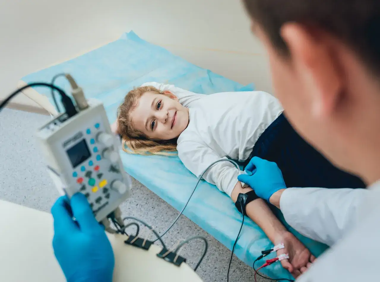 Lekarz bada dziecko z nietypowymi objawami padaczki, podłączając elektrody do jego ręki.