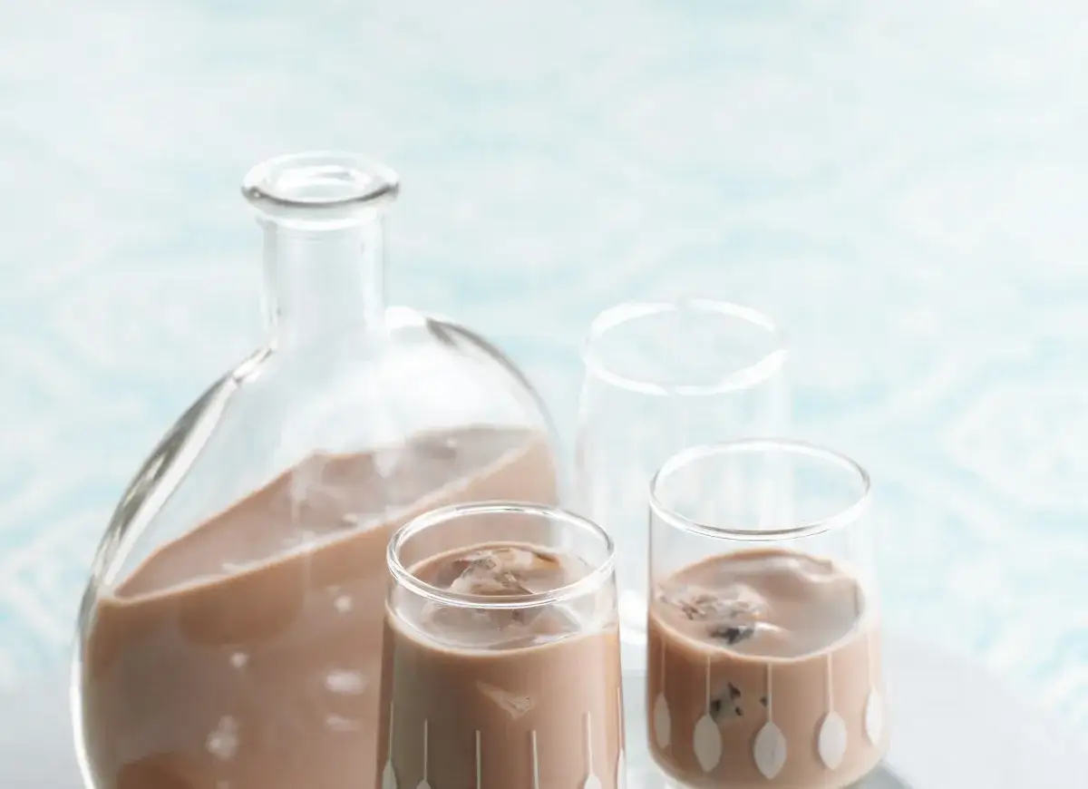 Domowy likier czekoladowy z przepisu, podany w szklaneczkach z lodem i karafce.